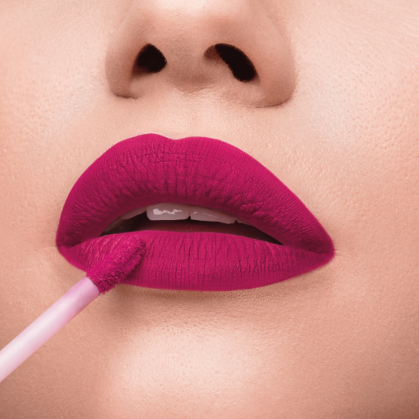 Lábios femininos aplicando batom líquido magenta mate