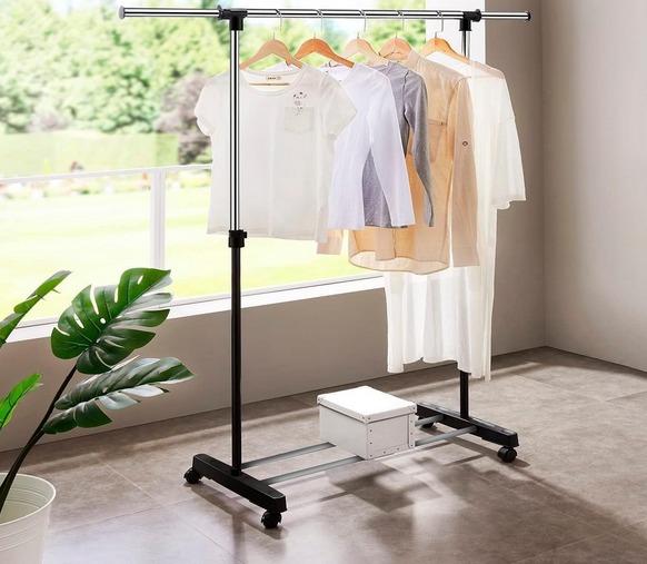 Varão para roupas de metal preto com cinco peças penduradas, planta e caixa branca no interior