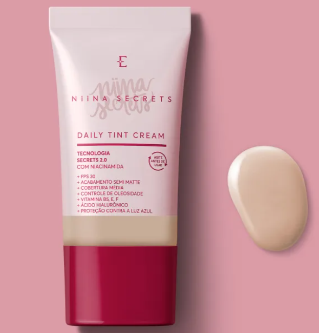 Frasco de creme diário com coloração NIINA SECRETS em tubo rosa e vermelho com amostra do creme ao lado