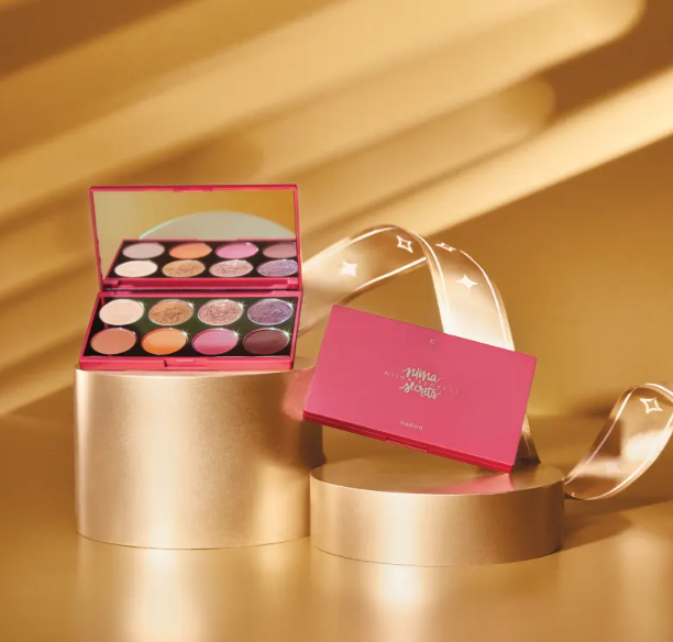 Paleta de sombra de olhos rosa com espelho e várias cores sobre suporte dourado.