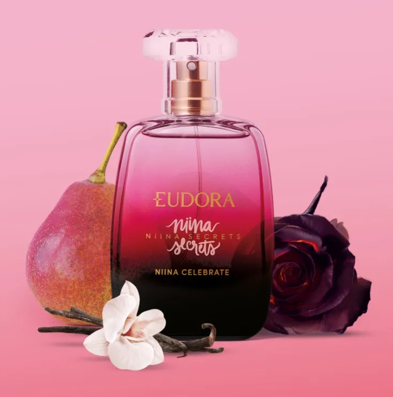 Perfume Eudora Niina Secrets Niina Celebrate com pera, flores e baunilha em fundo rosa