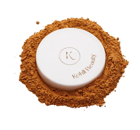 Pó compacto de maquilhagem com embalagem branca e texto Kohll Beauty rodeado por pó castanho