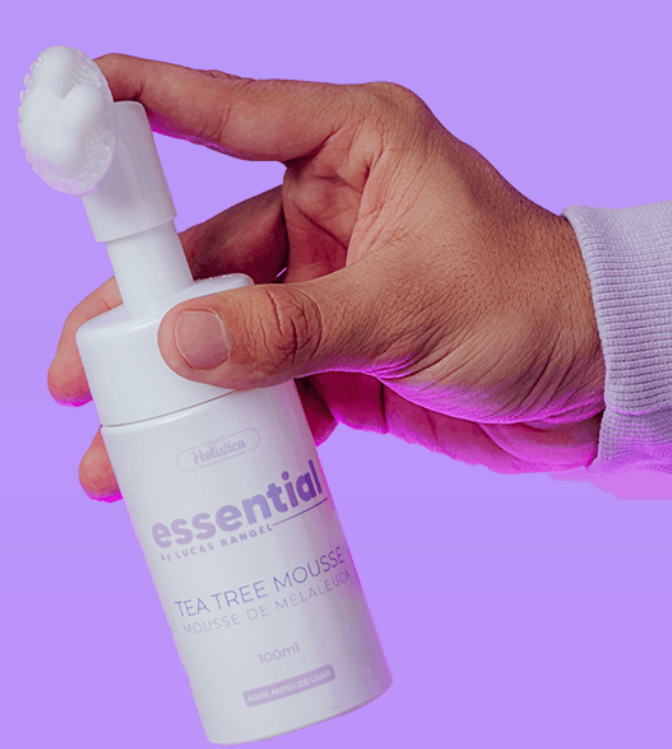 Frasco branco de mousse de Tea Tree segurado por uma mão em fundo roxo
