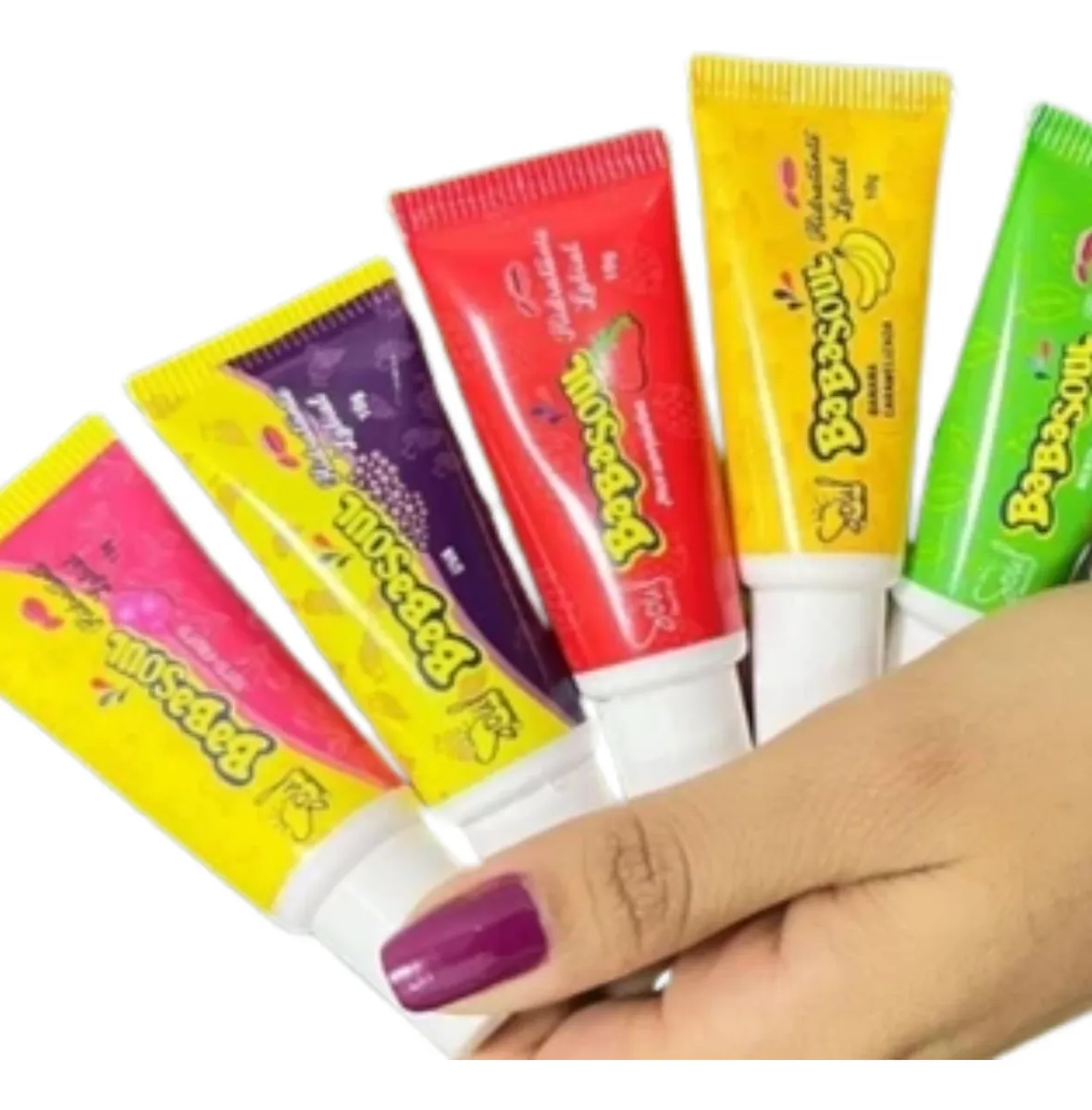 Tubos coloridos de creme BeBoSouL segurados por mão com unha roxa