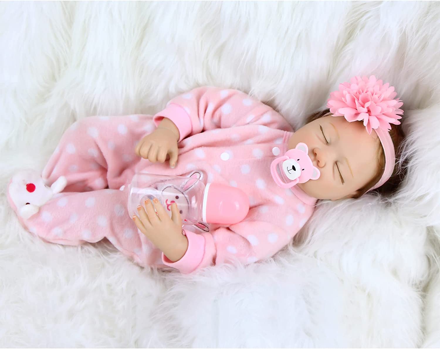 Boneca bebé em fato rosa com bolinhas brancas e fita de cabelo com flor