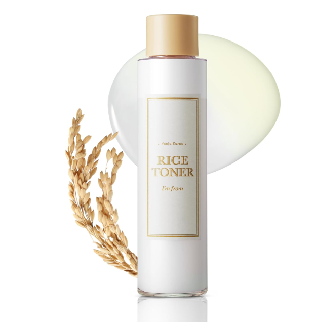 Frasco branco com tampa dourada de toner Rice com ramo de arroz seco e mancha translúcida ao fundo