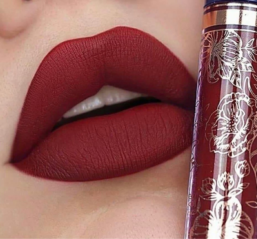 Lábios com batom vermelho matte e frasco de batom líquido com padrão floral