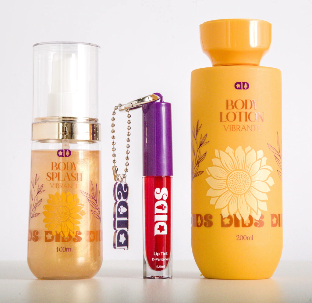 Conjunto de produtos cosméticos incluindo body splash, lip tint e body lotion com design floral amarelo e texto laranja.