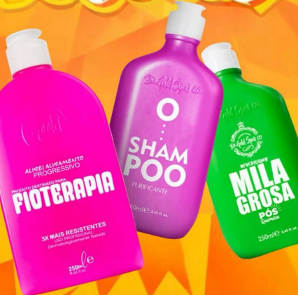 Produtos de cabelo com embalagens rosa, roxa e verde sobre fundo amarelo e laranja