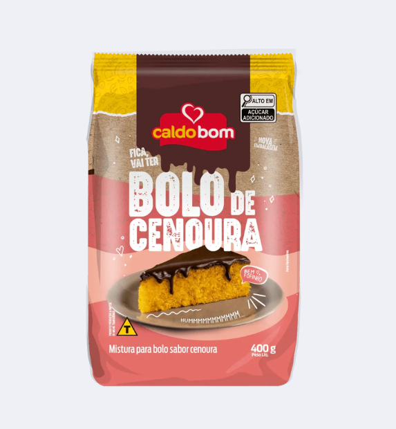 Mistura para bolo de cenoura Caldo Bom em embalagem rosa e castanha com fatia de bolo coberta de chocolate