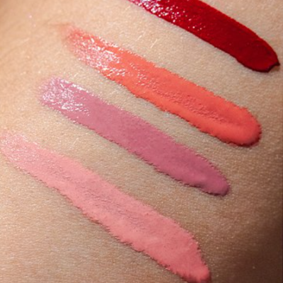 Quatro traços de batom líquido em diferentes tons sobre pele.