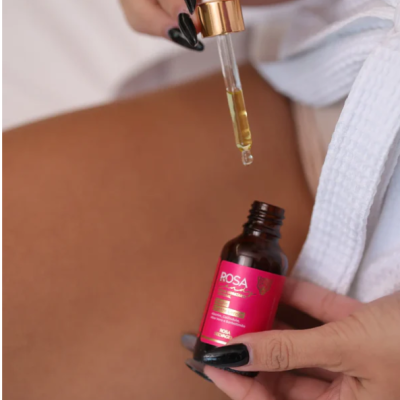 Frasco com conta-gotas e rótulo rosa junto a pele e roupão branco