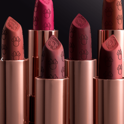 Seis batons com embalagem metálica rosa dourado e padrão gravado de cabeça de rato e brasão decorativo