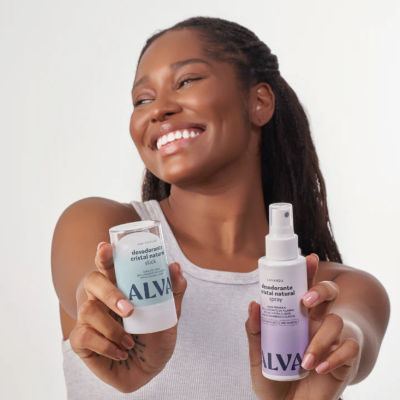 Mulher segura dois desodorizantes ALVA, stick azul claro e spray lilás