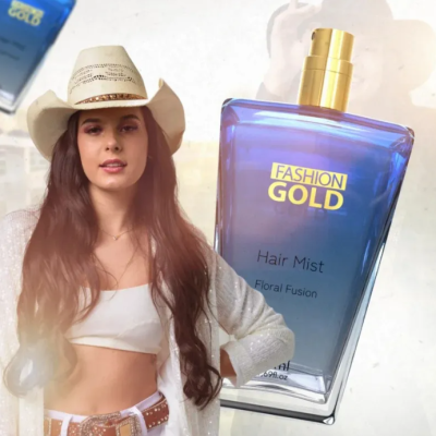 Jovem com chapéu e frasco de spray azul FASHION GOLD Hair Mist Floral Fusion.
