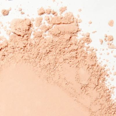 Pó compacto bege claro esfarelado sobre fundo branco