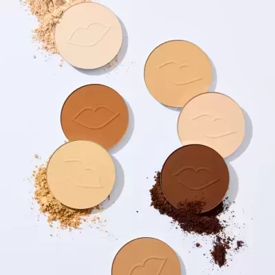 Pós compactos em vários tons com desenho de lábios em relevo sobre fundo branco.