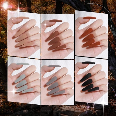 Mãos femininas com unhas postiças em diferentes cores mate, sobre fundo de floresta outonal