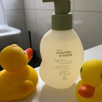 Frasco de sabonete líquido com dois patos de borracha amarelos num ambiente de casa de banho