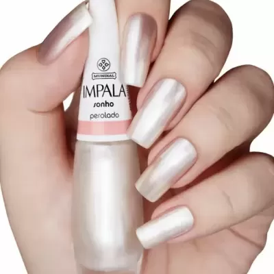 Frasco de verniz de unhas perolado Impala sonho segurado por mão com unhas pintadas