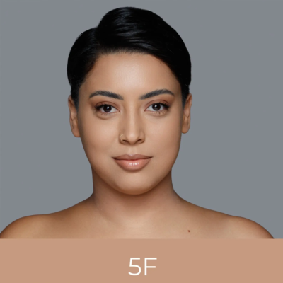 Mulher com maquilhagem natural e cor 5F em fundo cinzento e bege