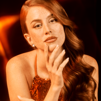 Mulher ruiva com vestido laranja brilhante e brincos prateados