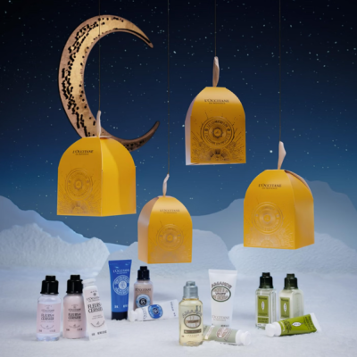 Produtos cosméticos LOCCITANE com embalagens pequenas e caixas amarelas suspensas no fundo azul estrelado
