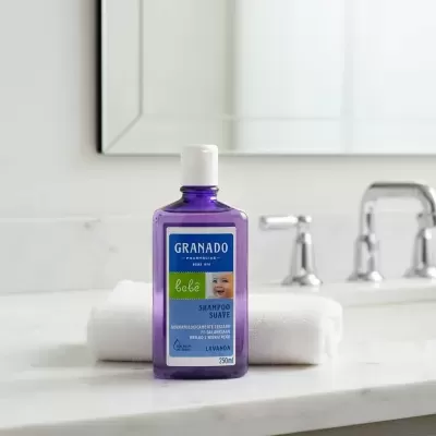 Frasco de shampoo suave para bebés Granado sobre toalha branca no lavatório.