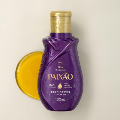 Frasco roxo de óleo corporal Paixão com tampa dourada e óleo amarelo ao lado