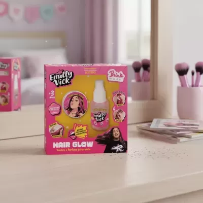 Produto cabelo Emilly Vick Hair Glow com spray e glitter em caixa rosa e amarela à frente de espelho e pincéis cor-de-rosa