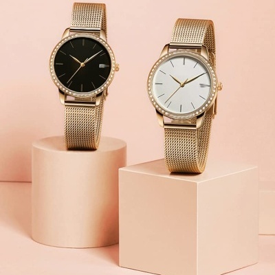 Dois relógios femininos dourados com mostradores preto e branco e braceletes de malha metálica