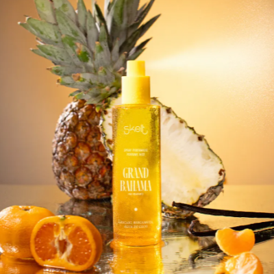 Frasco amarelo translúcido de spray perfumado com frutas tropicais em fundo dourado