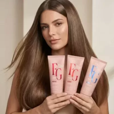 Mulher a segurar tubos de produtos de beleza com letras FG em rosa, vermelho e azul