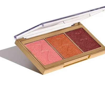 Paleta de maquilhagem com três tons de blush ou iluminador em caixa dourada com tampa transparente.