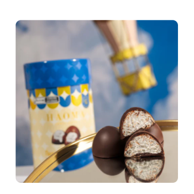 Bombons de chocolate com recheio branco e embalagem azul e amarela com padrão geométrico sob céu azul