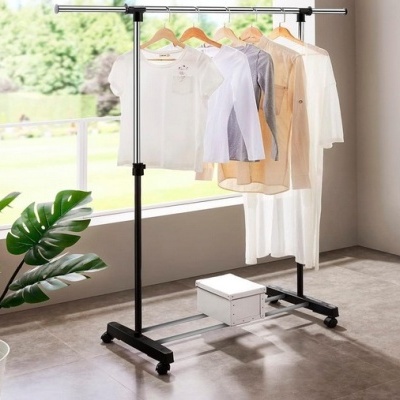 Varão para roupas de metal preto com cinco peças penduradas, planta e caixa branca no interior