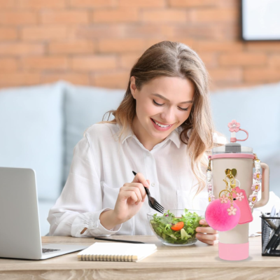 Garrafa de água rosa decorada numa mesa com mulher a comer salada ao fundo