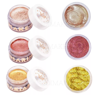 Três maquilhagens em potes com tampas brancas e texto dourado em fundo branco