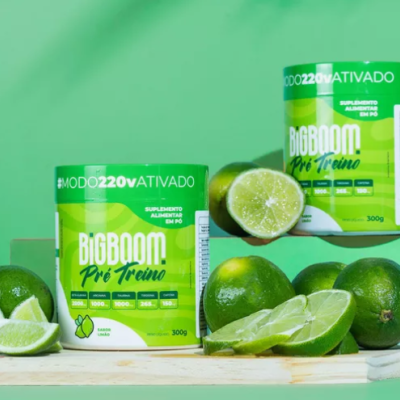 Suplemento alimentar BigBoom Pré-Treino sabor limão com limas frescas ao redor em fundo verde