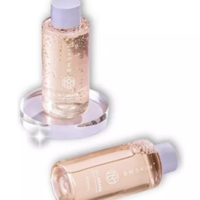 Duas garrafas transparentes com líquido rosa, tampas lilases, texto BM SKIN e OIL GRAPE