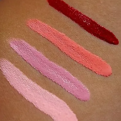 Quatro traços de batom em pele, em tons de rosa e vermelho.