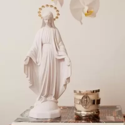 Estátua branca religiosa com vela decorativa sobre livros