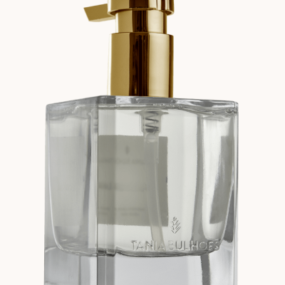 Frasco quadrado de vidro transparente com bomba dourada e líquido dentro