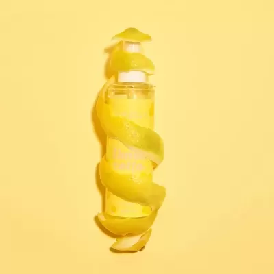 Frasco de spray com rótulo amarelo e casca de limão em espiral