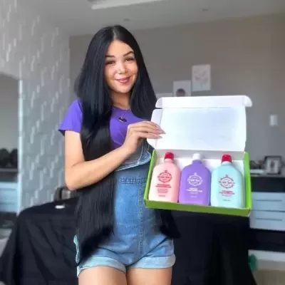 Mulher com cabelo longo a segurar caixa com três frascos coloridos dentro