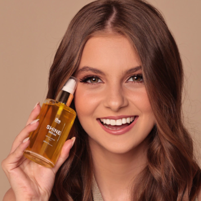 Frasco de serum amarelo com conta-gotas branco segurado por jovem sorridente
