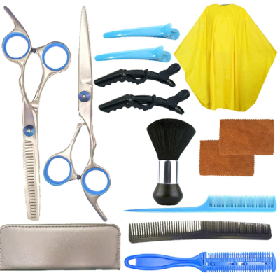 Conjunto para cabeleireiro com tesouras, presilhas, capa amarela, escova, toalhas, pentes e estojo cinzento.