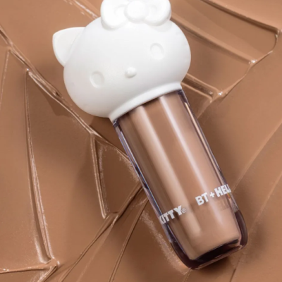 Embalagem de cosmético com tampa branca em formato de Hello Kitty e líquido cor de caramelo