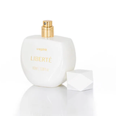 Frasco branco de perfume Liberté com pulverizador dourado e tampa branca ao lado