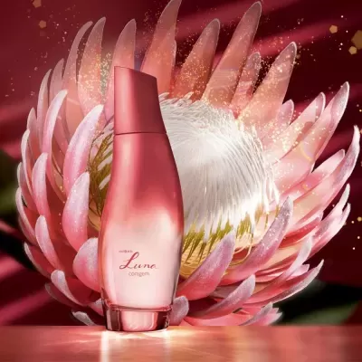 Frasco de perfume rosa em fundo com flores cor-de-rosa
